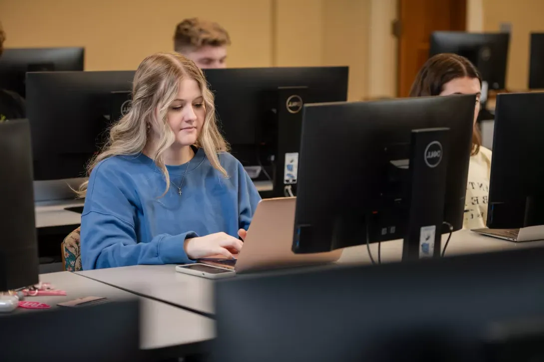 student typing on laptop